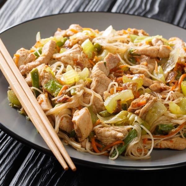 Chicken pancit bihon with vegetables and chopsticks on a gray plate from New Chinese Kitchen.