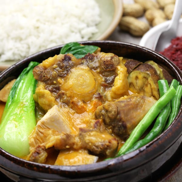 A close-up of Kare-kare, a Filipino stew with oxtail, vegetables, and peanut sauce, served with rice.